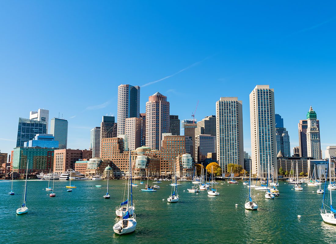 Boston, MA - City Skyline View of Commercial Buildings in Downtown Boston Massachusetts Next to the Harbor with Sail Boats on a Sunny Day